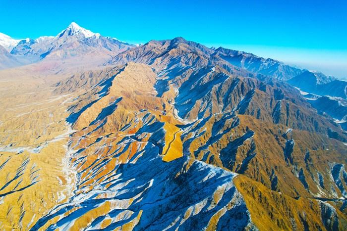 新疆阿克蘇山區雪后壯美巍峨 陽光下群山黃白相間